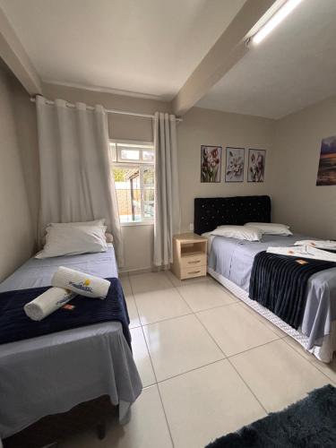 a bedroom with two beds and a window at Casa com piscina Aquecida Balneário Camboriú CasaAlbertiBc in Balneário Camboriú
