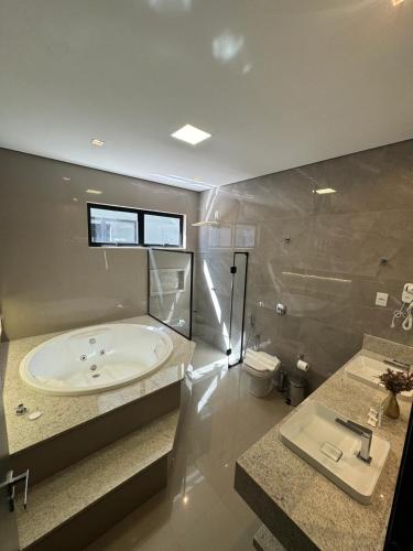 a large bathroom with a tub and a sink at Hotel Bonfim in Silvânia