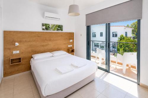 a bedroom with a large white bed and a balcony at Julipapas Gardens in Paphos