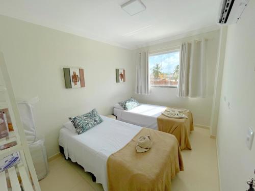 a white room with two beds and a window at Top-Flat @ Bella Maré in Maragogi