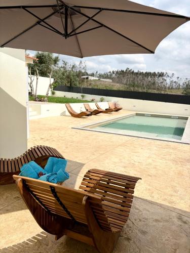 a patio with an umbrella and chairs and a pool at Refúgio D'Aldeia in Leiria