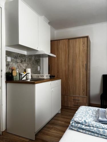 a kitchen with white cabinets and a bed in a room at Studio Apartman M&S Apatin in Apatin