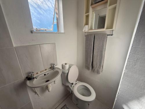 a white bathroom with a toilet and a sink at Suite Dreams Cute Studio Flat in Panorama