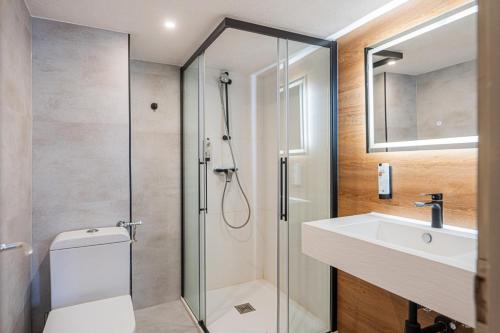 a bathroom with a shower and a toilet and a sink at Hotel Restaurant Jungfrau in Lauterbrunnen
