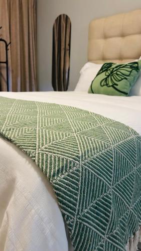 a bed with a green and white blanket on it at DL Apartments in Palatswe