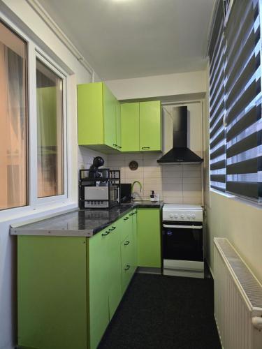 a kitchen with green cabinets and a stove at DeLux Apartment -Militari Residence Rosu Chiajna in Dudu