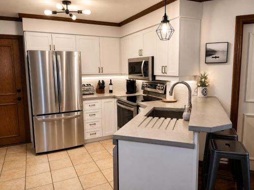 a kitchen with a stainless steel refrigerator and white cabinets at Superb ski inout - Ask about summer pool access! in Mont-Tremblant