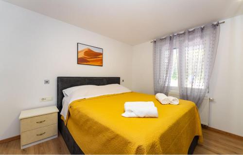 a bedroom with a yellow bed with two towels on it at Apartman in Seline