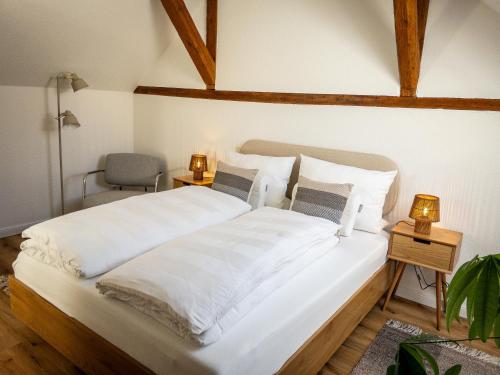 a bedroom with a large white bed and a chair at TINY TEUTO HOUSE- Die alte Schusterei in Detmold