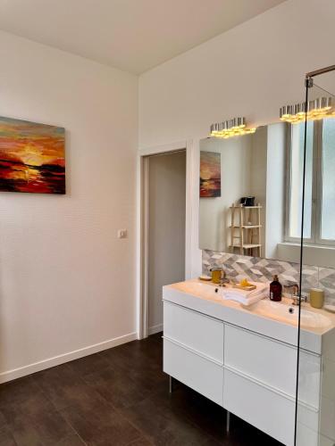 a white bathroom with a sink and a mirror at Les Meublés d'Etigny in Luchon