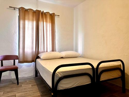 a bed in a room with a window and a chair at Sekretet e Luginës Restaurant - Hostel - Camping in Vau i Dejës