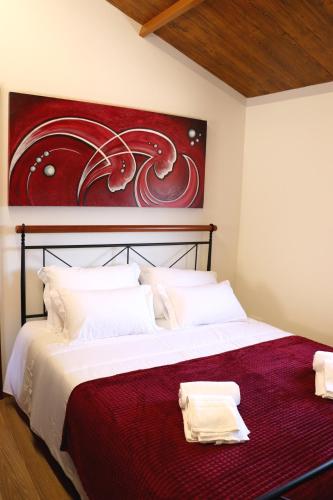 a bedroom with a large bed with a painting on the wall at Casa do Maninho in Amarante