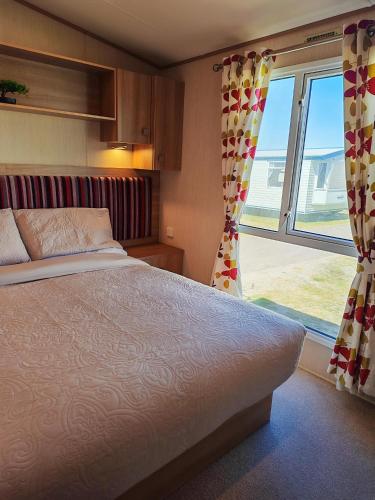 a bedroom with a bed and a large window at 9 Sea View Kessingland Beach Parkdean Resorts MIN 3 NIGHT STAY in Kessingland