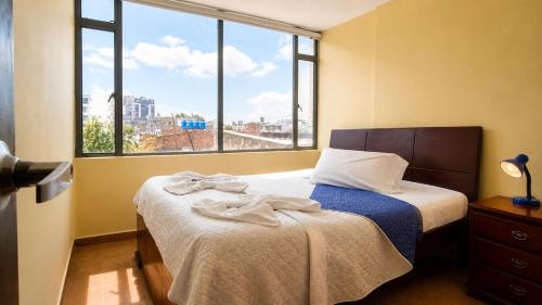 a bedroom with a bed and a large window at Apartamentos CasaMJ Tunja Confort y Parqueadero in Tunja