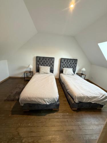 two twin beds in a room with two tables at La Clef des Champs in Mecquignies