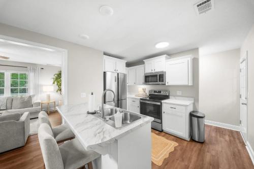 a kitchen and living room with white cabinets and a counter at GSU Getaway 4BR3BA spacious pet friendly in Statesboro