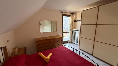 a bedroom with a red blanket and a mirror and a dresser at Appartamento Belvedere in Teglio