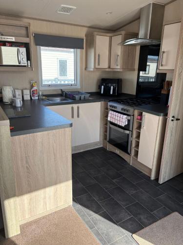 a kitchen with white cabinets and black counter tops at Sunrise in Selsey
