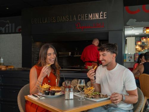 a man and a woman sitting at a table with food at ibis Orange Centre Echangeur A7 A9 in Orange