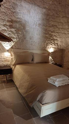 a bed in a room with a stone wall at Trulli Fichi Luxury Trullo with Private Spa and Saltwater Pool in Santa Lucia