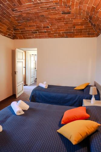 two beds in a room with blue and orange pillows at The River House in Bagnone