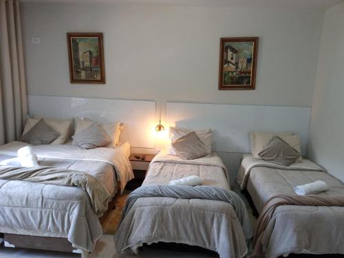 a room with three beds in a room at Pousada Casa Terra de Pinheiros in Santo Antônio do Pinhal