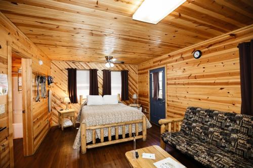 a bedroom in a log cabin with a bed and a couch at The Cabins at Pine Haven - Beckley in Beaver