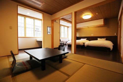 a room with two beds and a table and a bed at Nakajimaya Ryokan in Nozawa Onsen