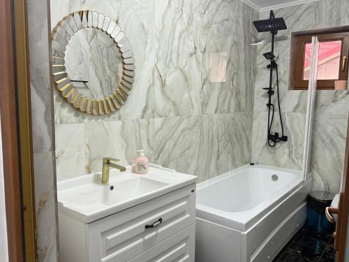 a bathroom with a sink and a tub and a mirror at Vila Dari in Tulcea