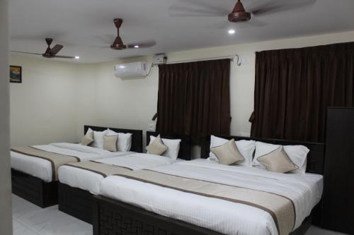 two beds in a hotel room with white pillows at Hotel GVP Residency in Tirupati