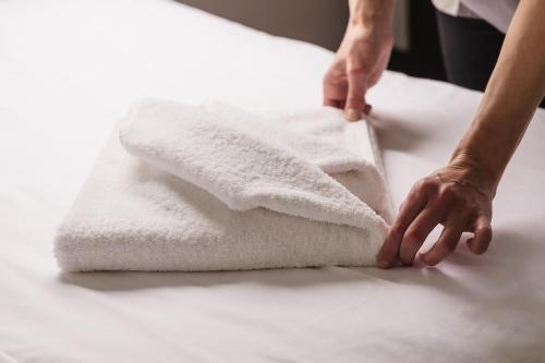 a person is folding towels on a table at San Teodoro Boutique Hotel in Korčula