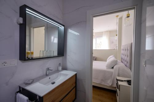 a bathroom with a sink and a mirror and a bed at Hotel Boutique Alcazaba Salobreña in Salobreña