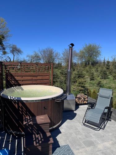 a hot tub and a chair on a patio at Domek na wzgórzu in Ukta