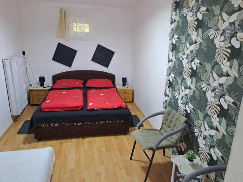 a bedroom with a bed with red pillows and a chair at Kisfaludy Vendégház in Abádszalók
