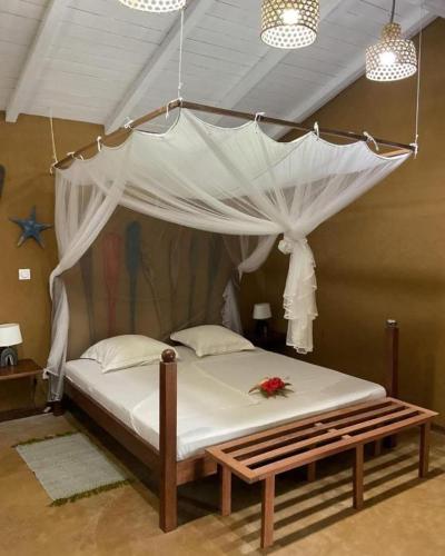 a bed with a canopy with a flower on it at Chez L'Avocatier in Sainte Marie