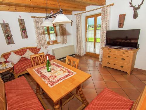 ein Wohnzimmer mit einem Tisch und einem Fernseher in der Unterkunft Alluring Holiday Home in Ubersee with Whirlpool in Übersee