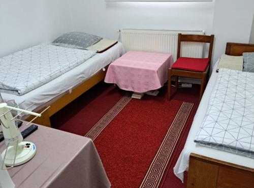 a room with two beds and a table and chairs at Rooms Đenadija in Hrvatska Kostajnica