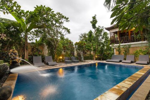 a pool with chairs and a water fountain at Tropical Bali Hotel in Sanur