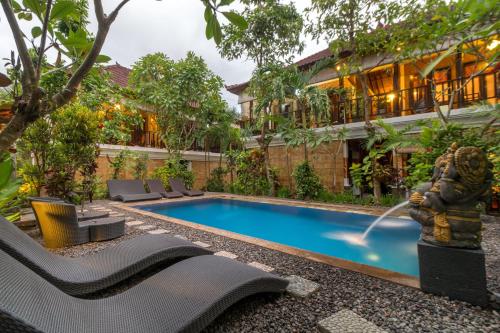 a swimming pool in front of a building with a fountain at Tropical Bali Hotel in Sanur