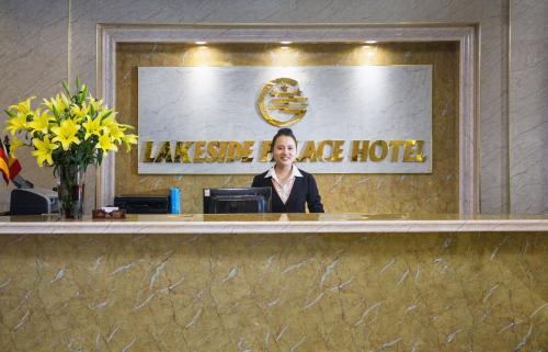 a woman sitting at a reception desk in a hotel at Lakeside Palace Hotel in Hanoi