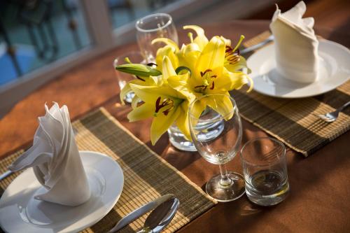 a table with white plates and a vase with yellow flowers at Lakeside Palace Hotel in Hanoi