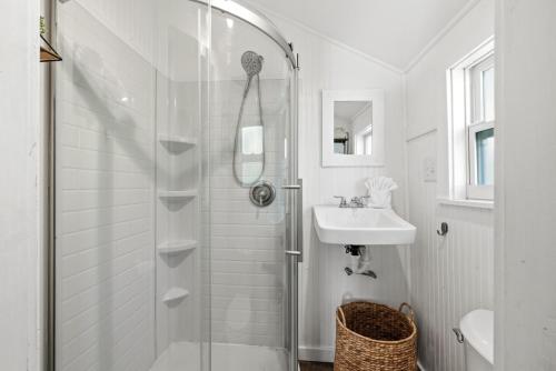 a white bathroom with a shower and a sink at Fisher Flats Downstairs in Cedar Key