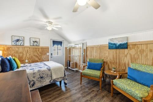 a bedroom with a bed and two chairs at Fisher Flats Downstairs in Cedar Key