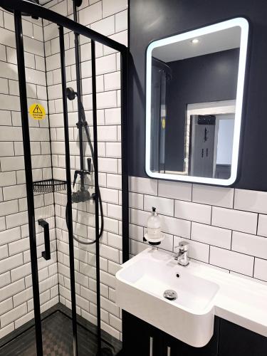 a bathroom with a sink and a shower with a mirror at The Old Court House & Jail in Menai Bridge