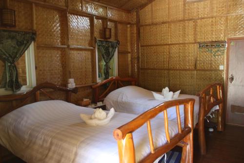 ein Schlafzimmer mit zwei Betten mit Hüten darauf in der Unterkunft Soe Ko Ko Beach House & Restaurant in Ngwesaung