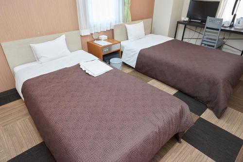 a hotel room with two beds and a television at Hotel Select Inn Utsunomiya in Utsunomiya