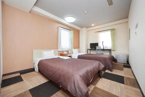 Hotel Select Inn Utsunomiya في أوتسونوميا: غرفة فندقية بسريرين ومكتب