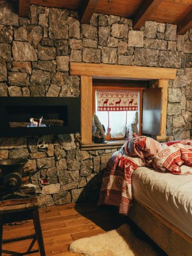 a bedroom with a stone wall with a bed and a window at ALLA STALLA Suite & Chalet in Piazzatorre
