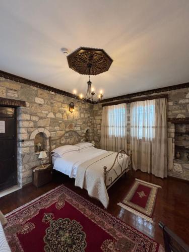 a bedroom with a large bed and a stone wall at Boutique Hotel Vila Aleksander in Berat