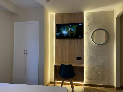 a bedroom with a tv on a wall with a chair at Hotel Alain by Dynamic Hotels in Silla